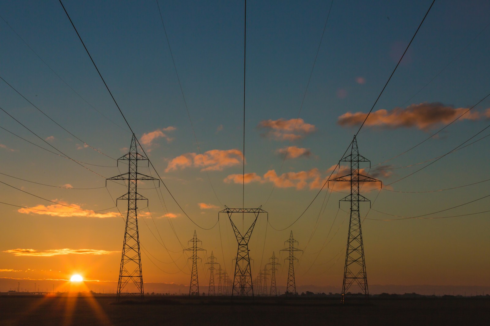 夕暮れの送電鉄塔とAIデータセンター向け電力インフラのイメージ